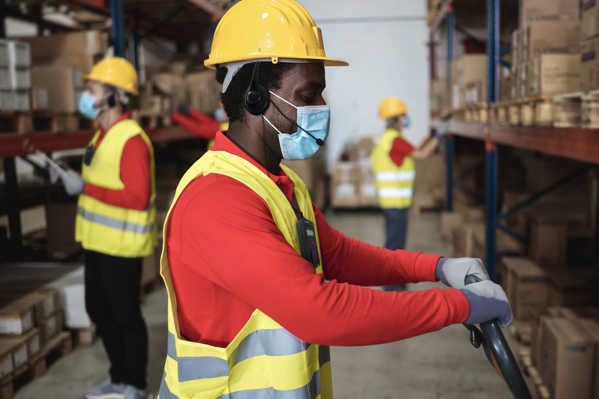 warehouse worker loading delivery boxes while wearing mask